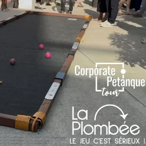 Terrain de pétanque mobile installé lors d’un événement d’entreprise en extérieur, avec plusieurs boules colorées en jeu et des participants visibles en arrière-plan.